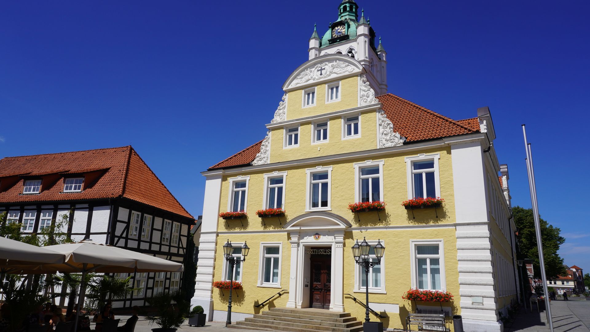 Historisches Rathaus Verden mit gelber Fassade, weißen Akzenten und dekorativen Blumenkästen.