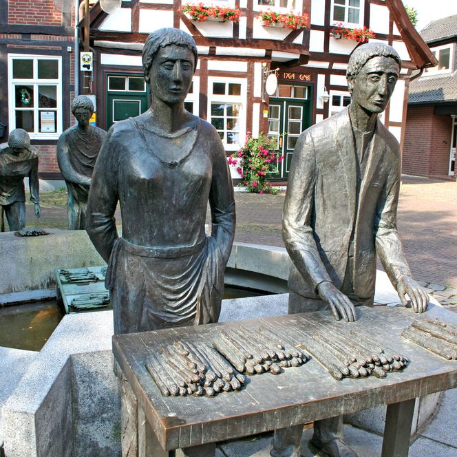 Bronzestatue einer Spargelerntetruppe in Nienburg, die stolz den Nienburger Spargel präsentiert.