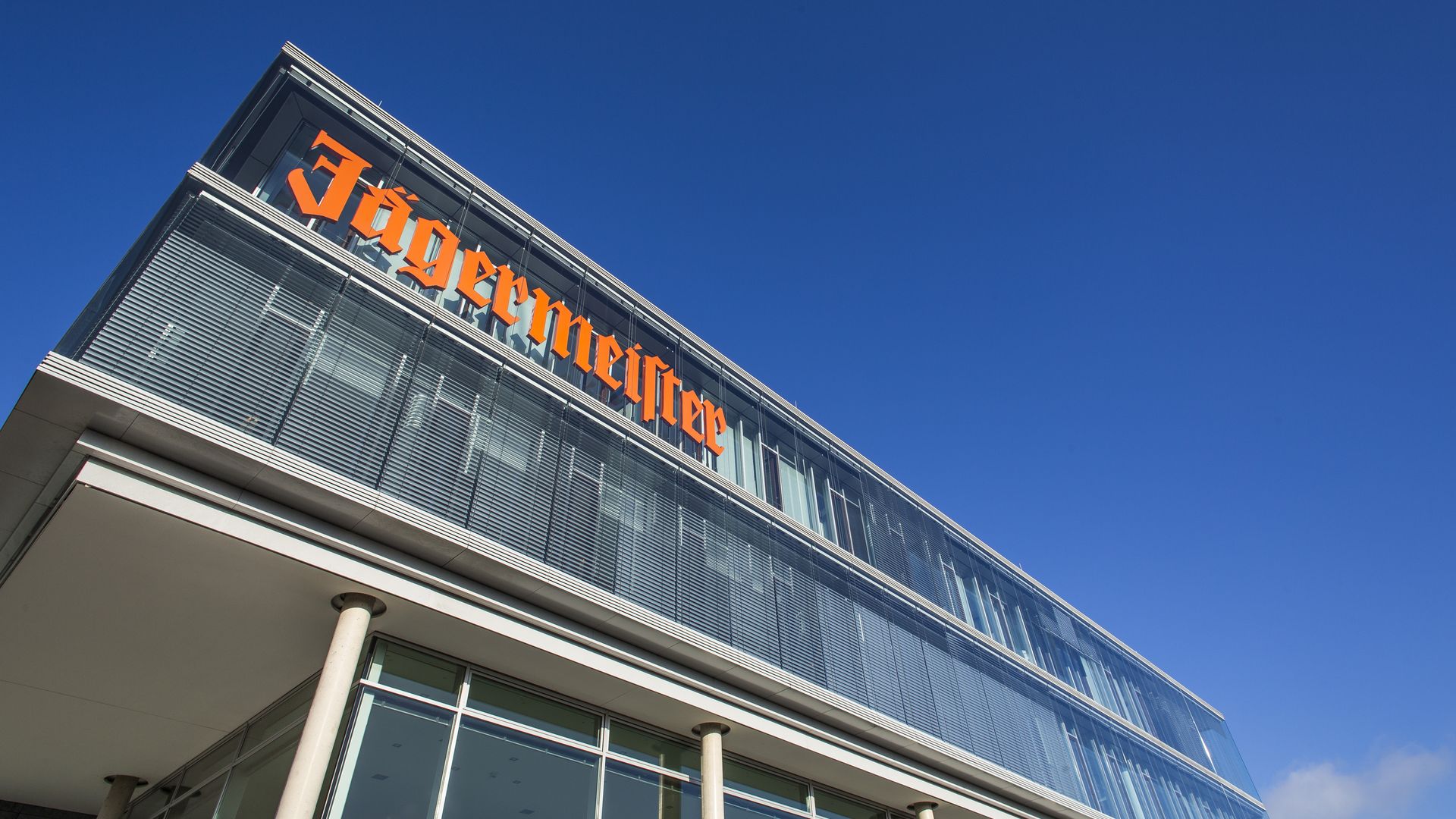 Modernes Glasgebäude der Firma Jägermeister unter blauem Himmel